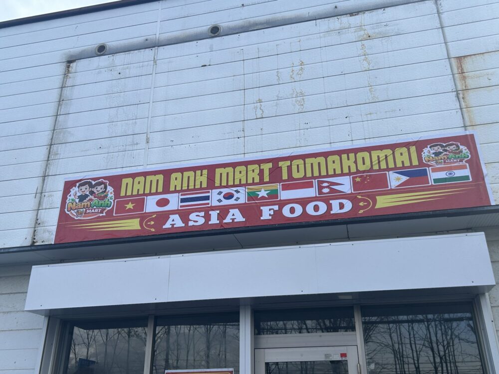 各国の国旗とASIA FOODの文字が並ぶNAM ANH MARTの赤い看板